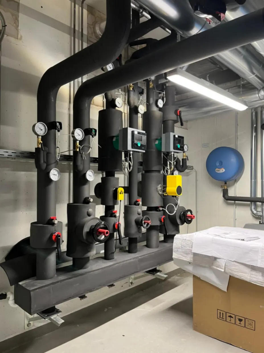 Gedämmter Heizungsverteiler mit Pumpen und Armaturen im Technikraum