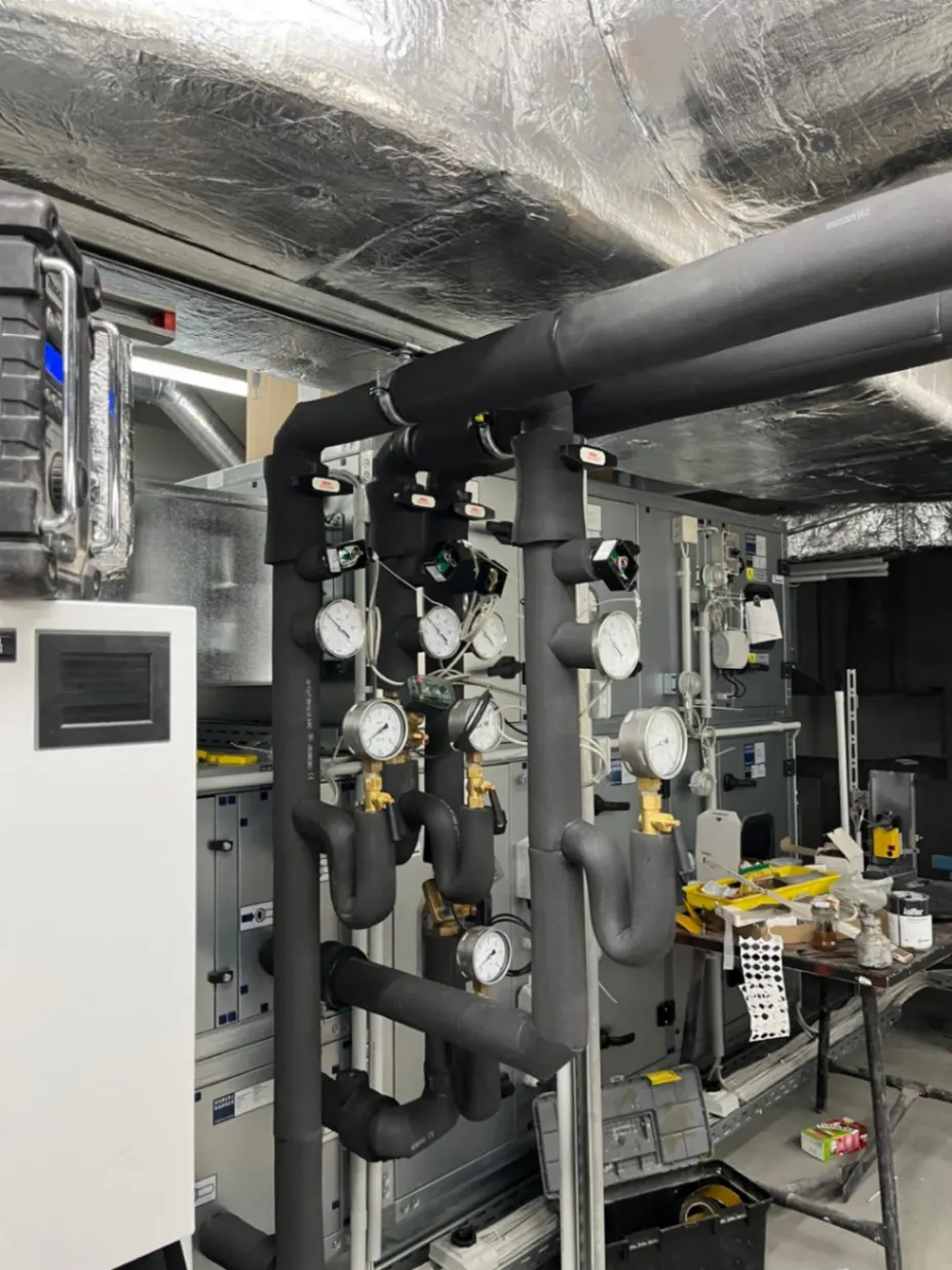 Schallgedämmte Rohrleitungen und Lüftungskanäle unter der Decke eines Technikraums